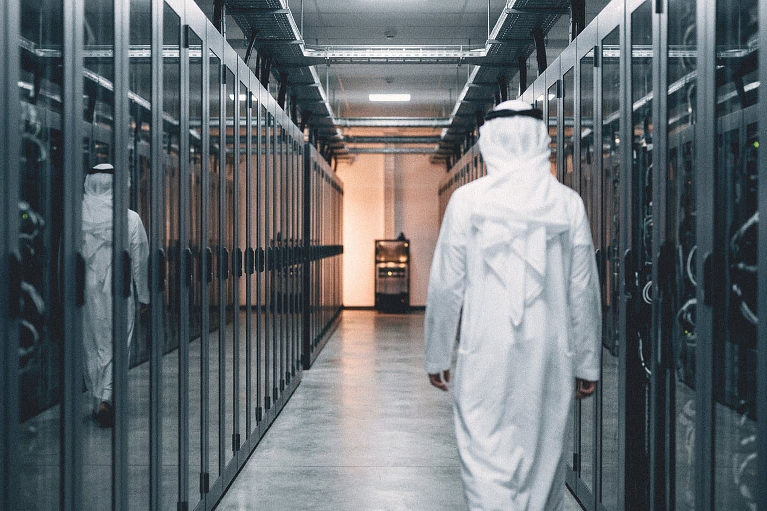 Engineer in traditional Gulf dress walking down a data centre server aisle