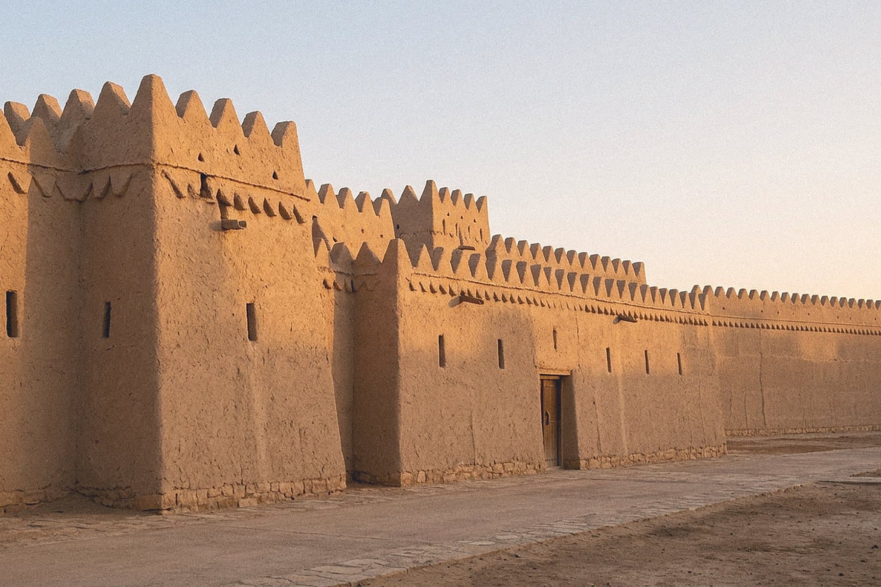 Restored mud-brick Najdi heritage walls with triangular crenellations in Riyadh