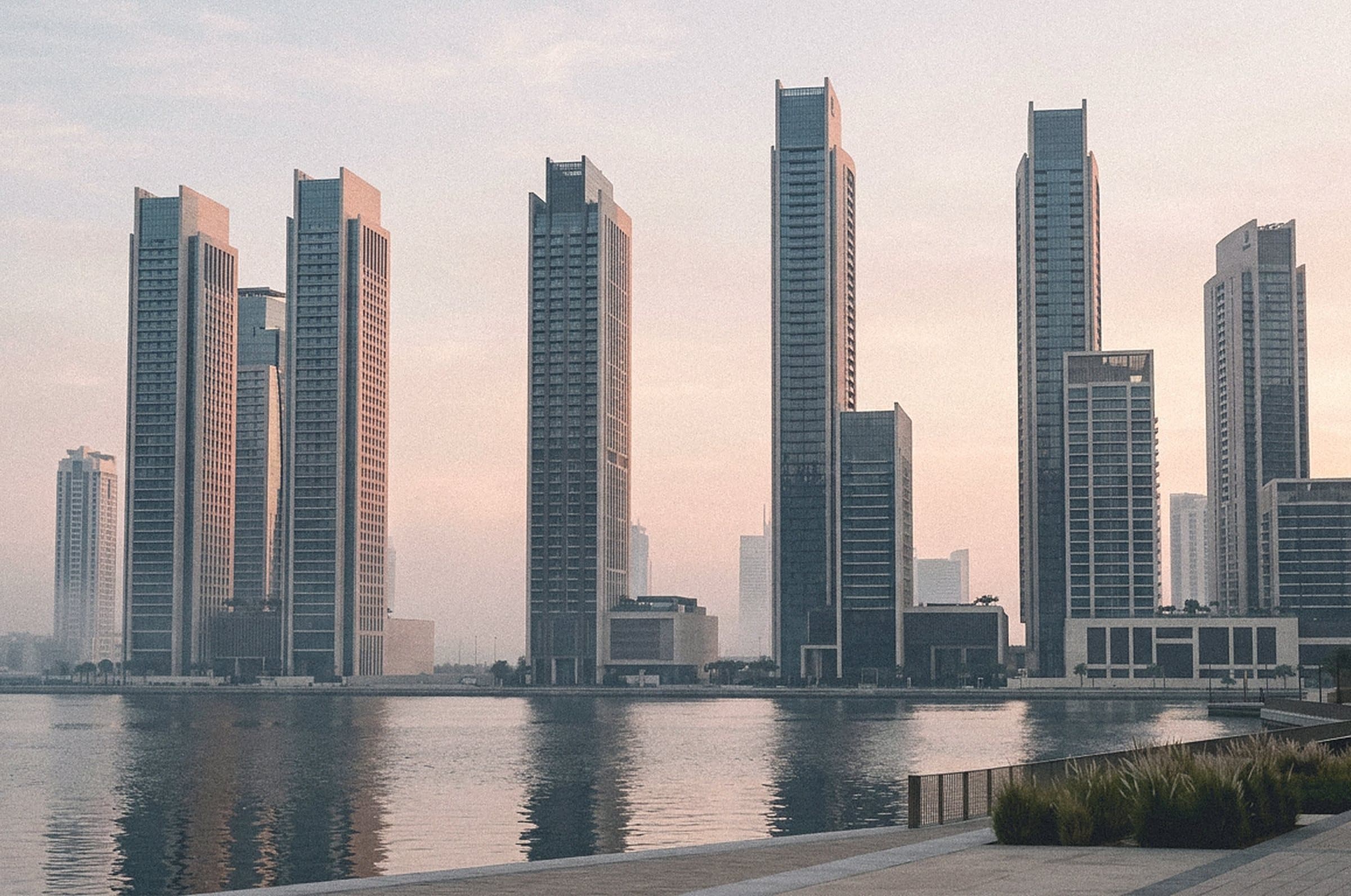 Residential towers along a waterway at dusk, reflected in calm water
